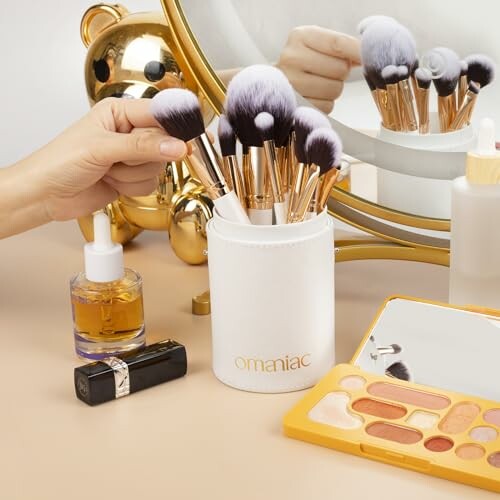 Hand arranging makeup brushes in holder with cosmetics on table.