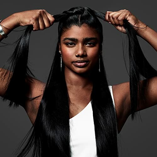 Woman with long black hair braiding her hair.