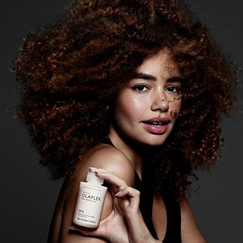 Woman with curly hair holding Olaplex hair product.